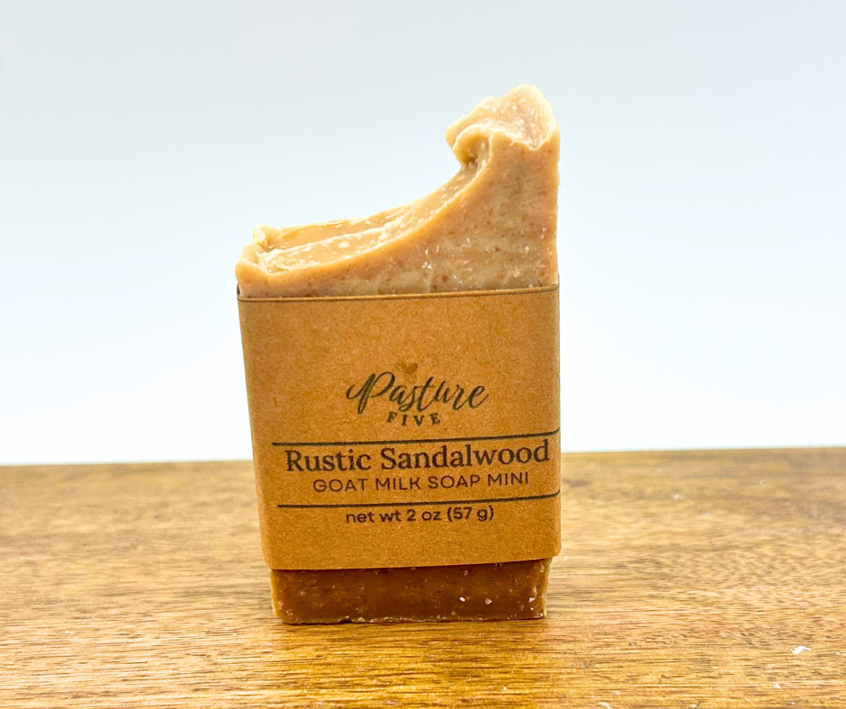 Half Bar of rustic sandalwood goat milk soap on a wooden surface with a white background