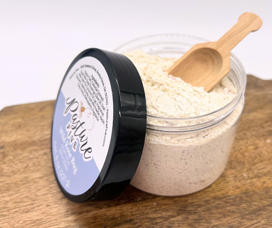 A container of Bath Soaks, spoon on a wooden board. 