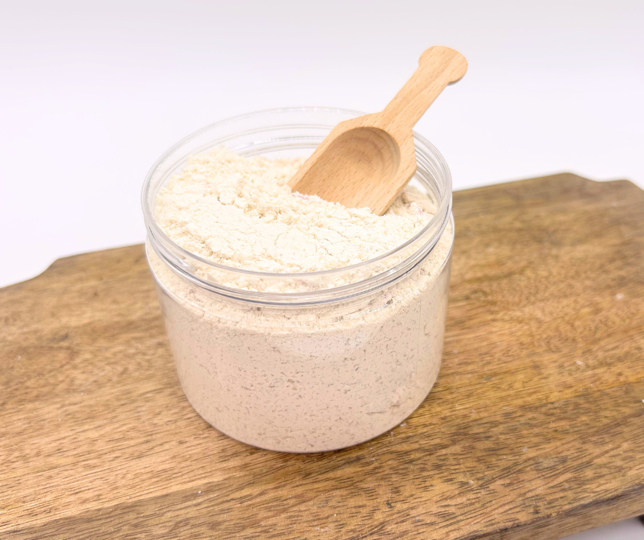 Jar of bath salts with a wooden spoon on a wooden board.