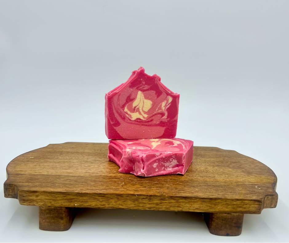 Pink  and white soap with a decorative design on a wooden stand against a white background