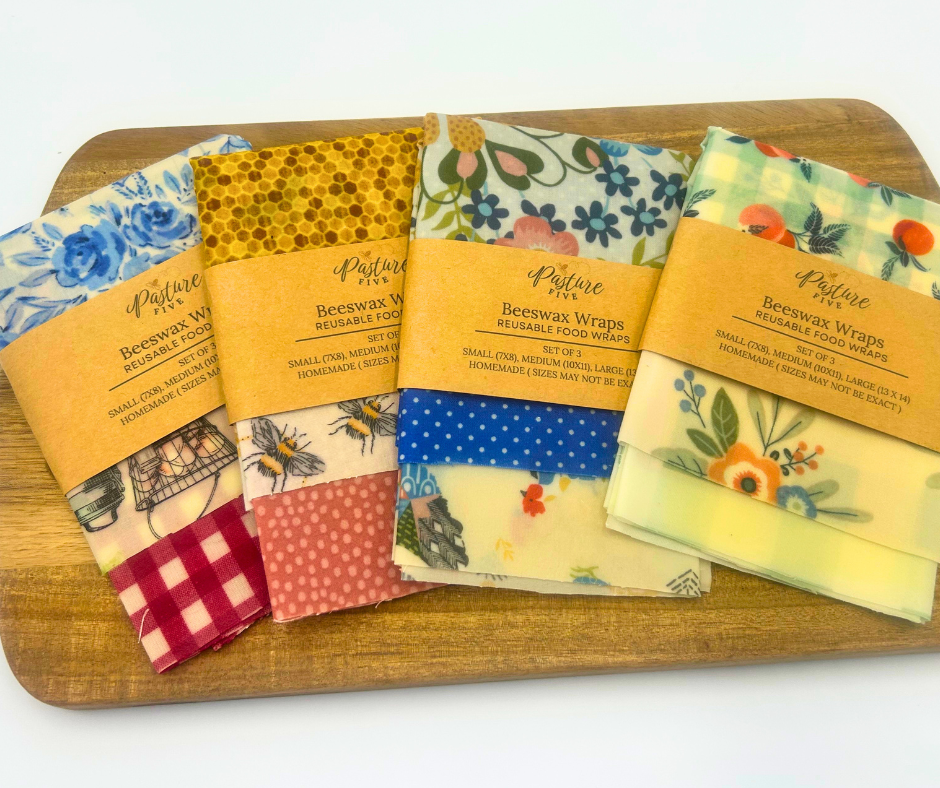 Sets of colorful beeswax wraps with Pasture Five labels on a wooden board.