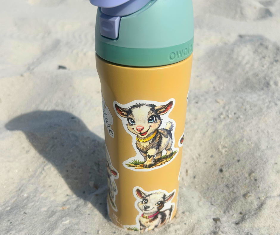Yellow water bottle with animal stickers on a sandy surface