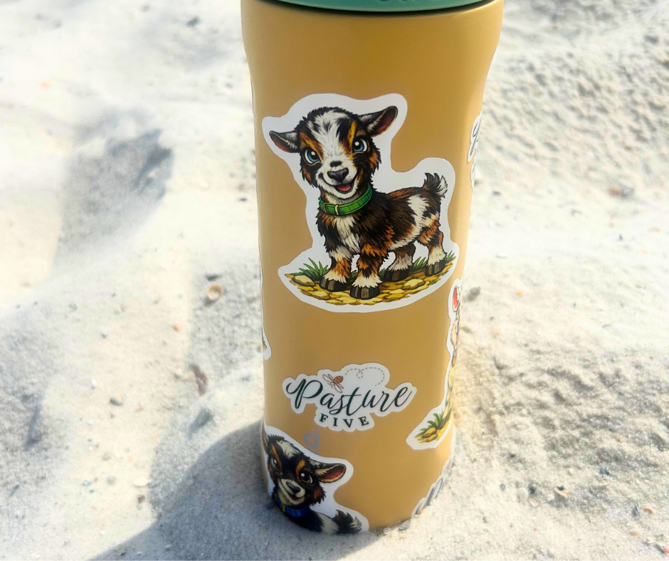 Yellow tumbler with a goat sticker on a sandy background