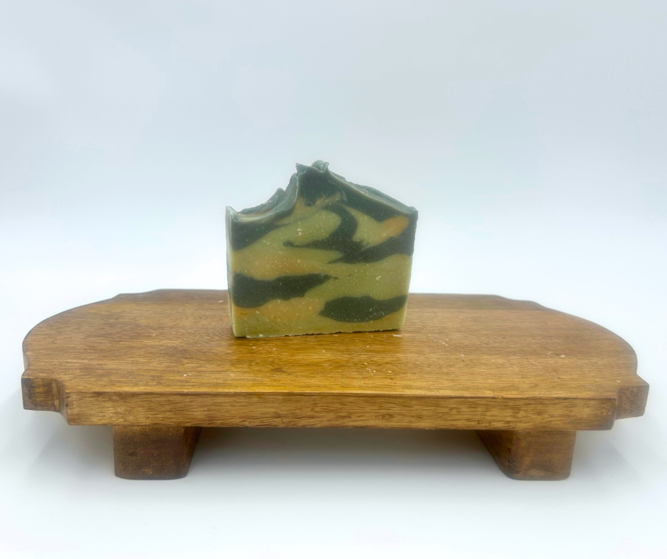Green and brown soap bar on a wooden stand against a white background