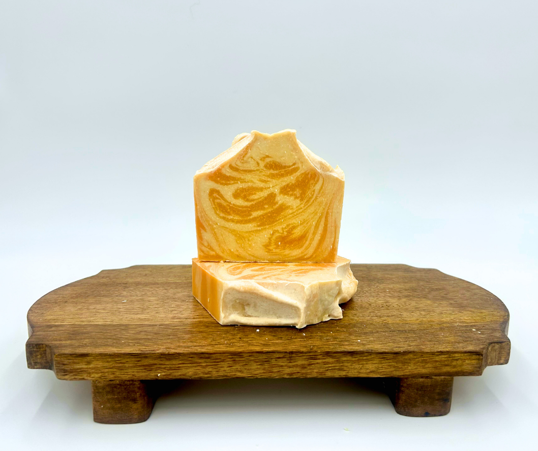 Two pieces of soap on a wooden stand with a white background