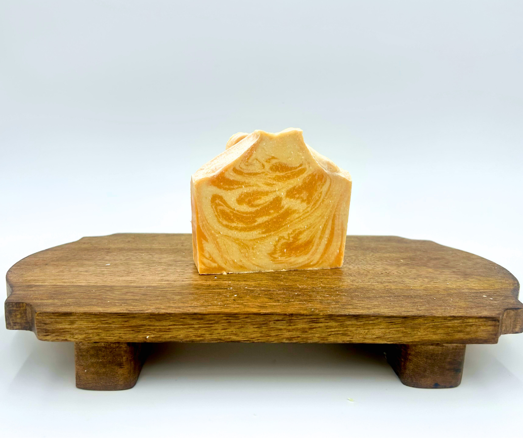 Orange and white designed soap on a wooden stand with a white background