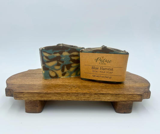 Two soap bars on a wooden stand with a label reading 'Blue Harvest' on a white background.