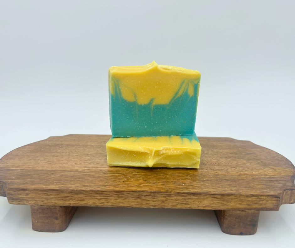 Two bars of soap, blue and  yellow, on a wooden block with a white background.