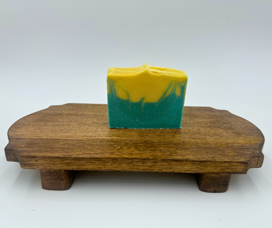 Bar of soap with blue and yellow gradient on a wooden stand against a white background