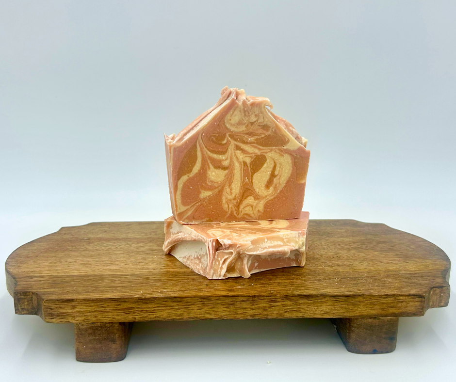 Bar of soap with decorative design on a wooden stand against a light gray background