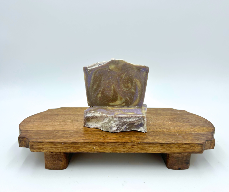 Two Soaps on a brown platform. Cedar Lavender, purple, brown, and Cream. 