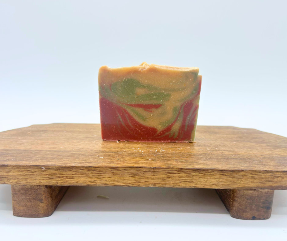One bar of Christmas Morning Goat Milk Soap on a wood board. 