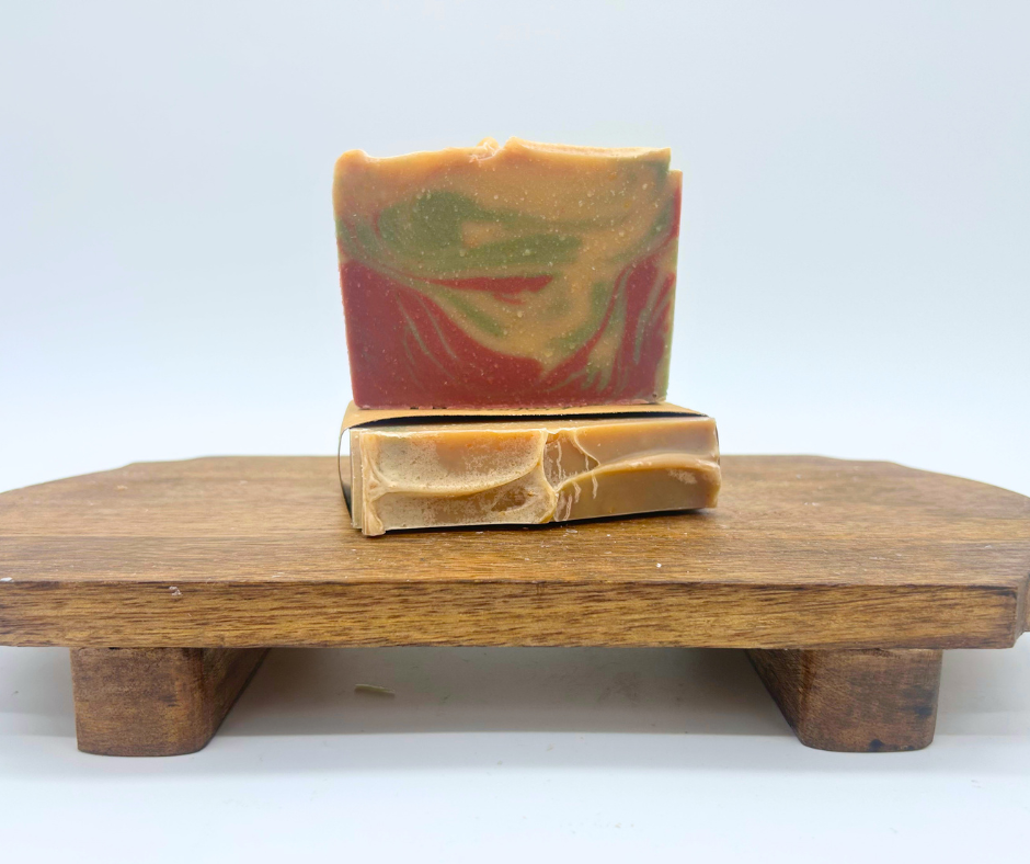 Two bars of Christmas Morning Goat Milk Soaps on a wood board. 