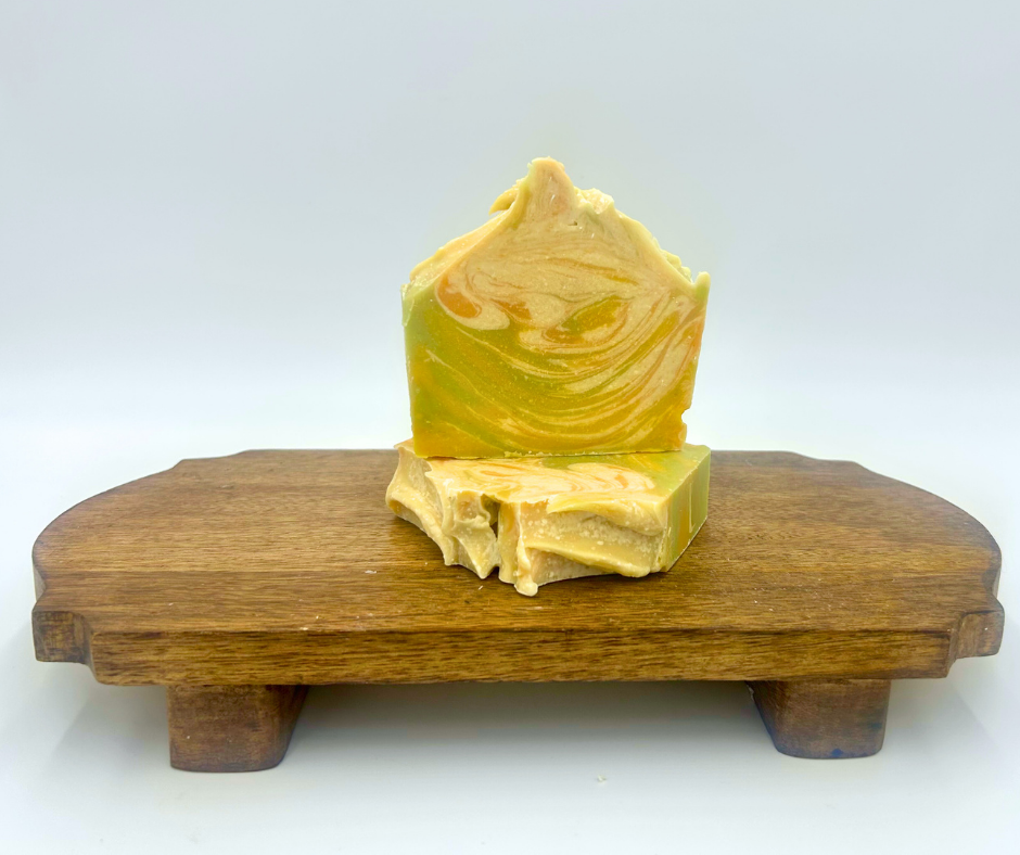Yellow, Orange and Green soap bar on a wooden stand with a white background
