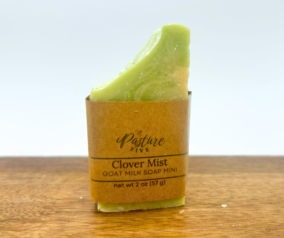 Mini Green soap bar in a brown paper wrap on a wooden surface with a light blue background