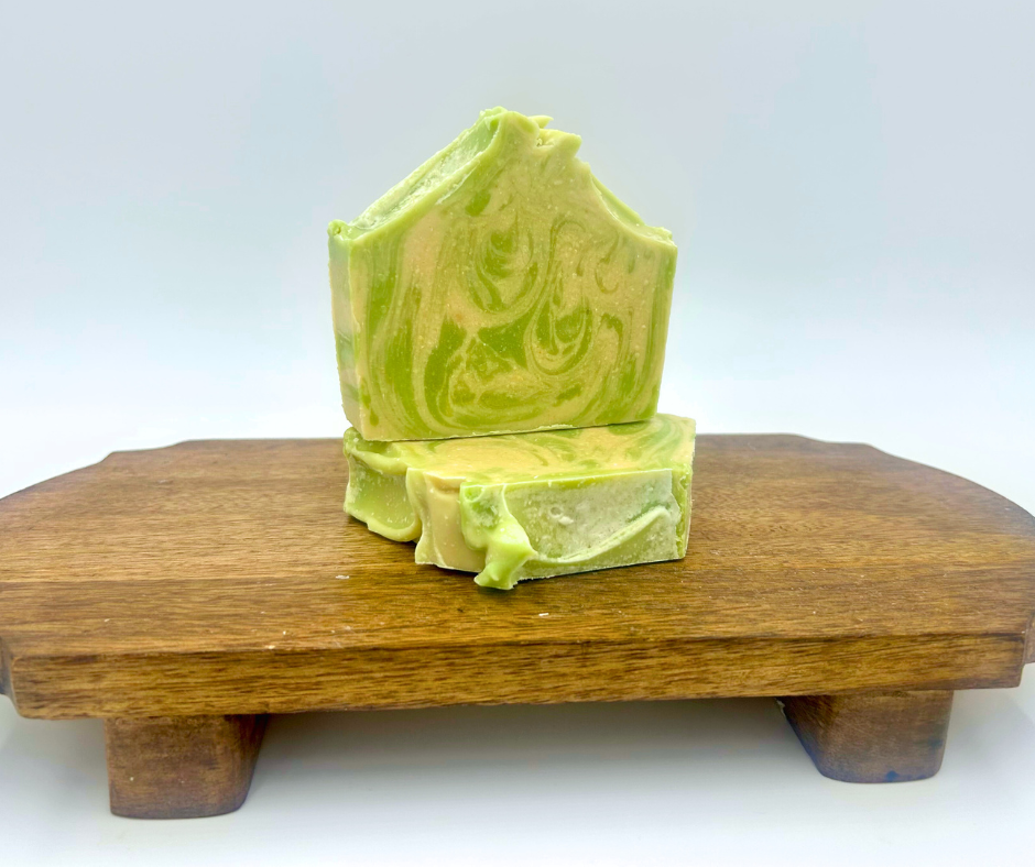 Green and white swirled soap on a wooden block with a white background