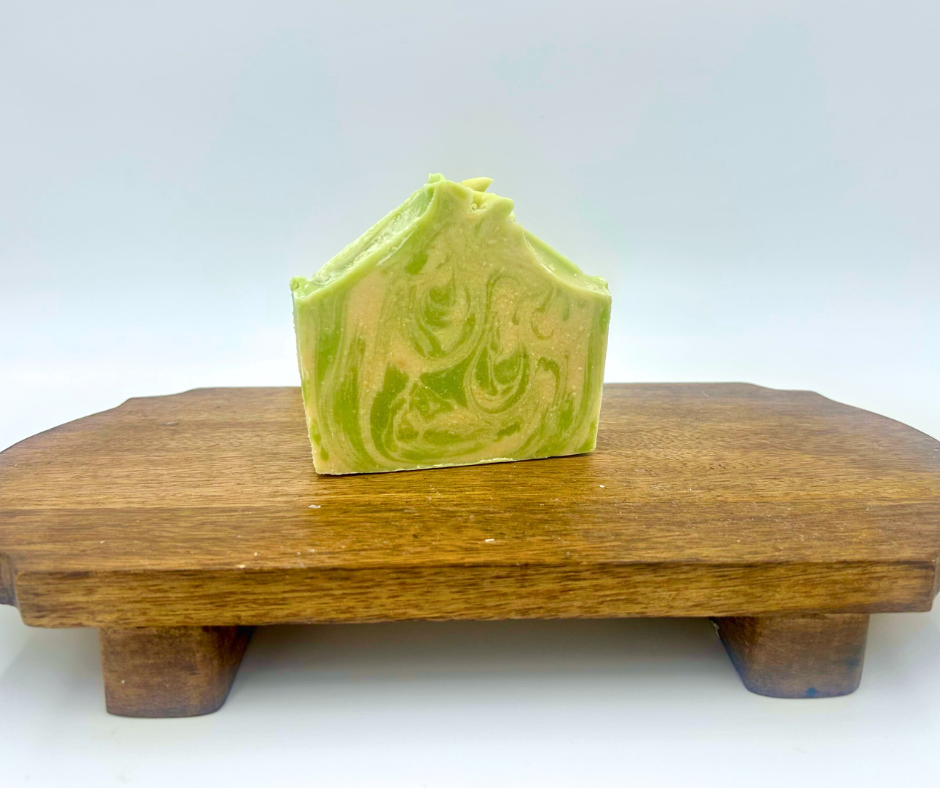 Green and white swirled soap bar on a wooden stand with a light gray background