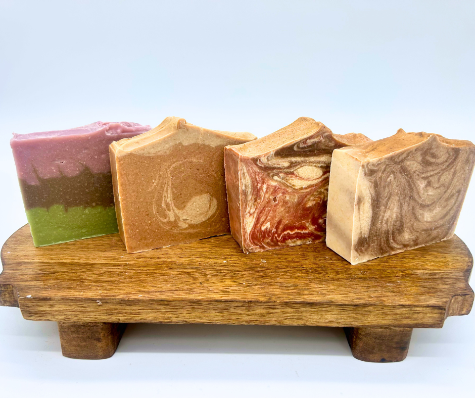 Four fall scent bars of soap on a wood board. Autumn Fig, Pumpkin Spice, Fireside, and Cashmere & Cocoa. 