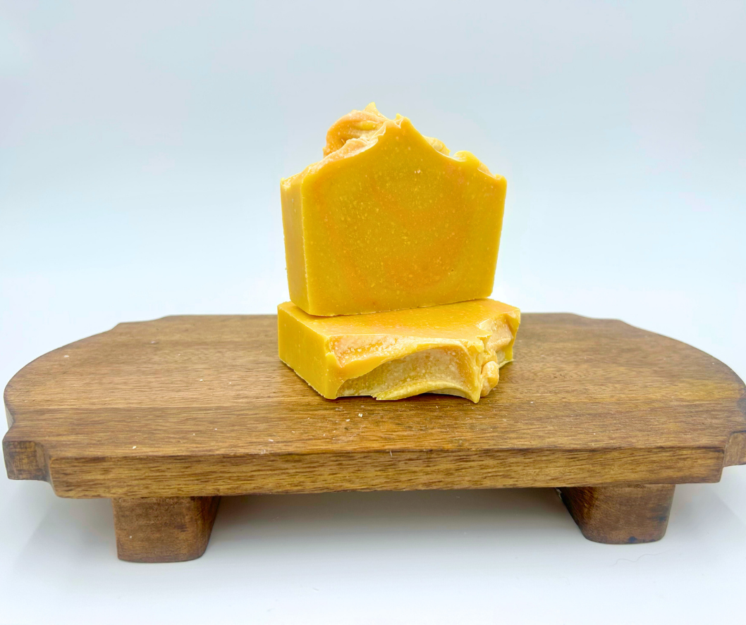 Two soap bars on a wooden stand with a white background