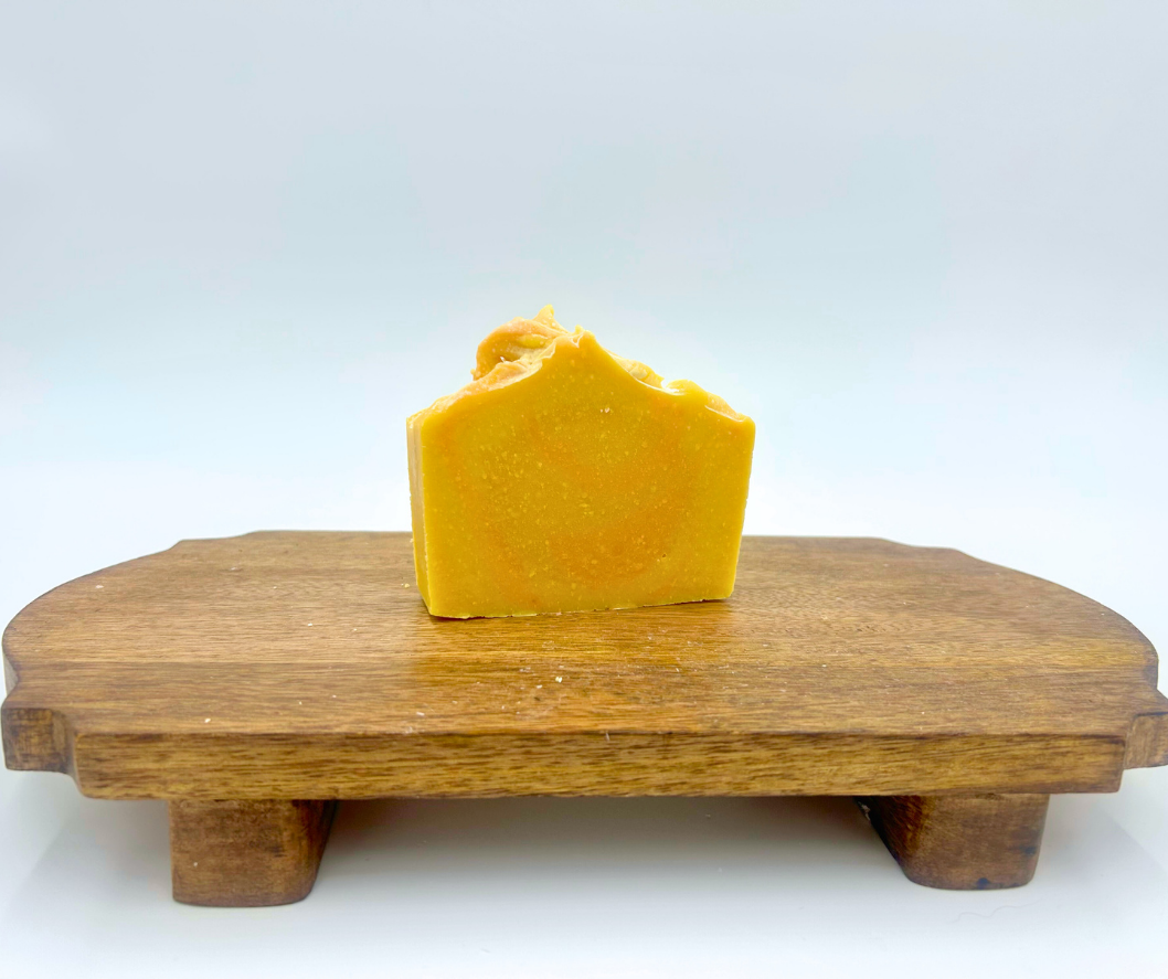 Bar of yellow soap on a wooden stand with a white background