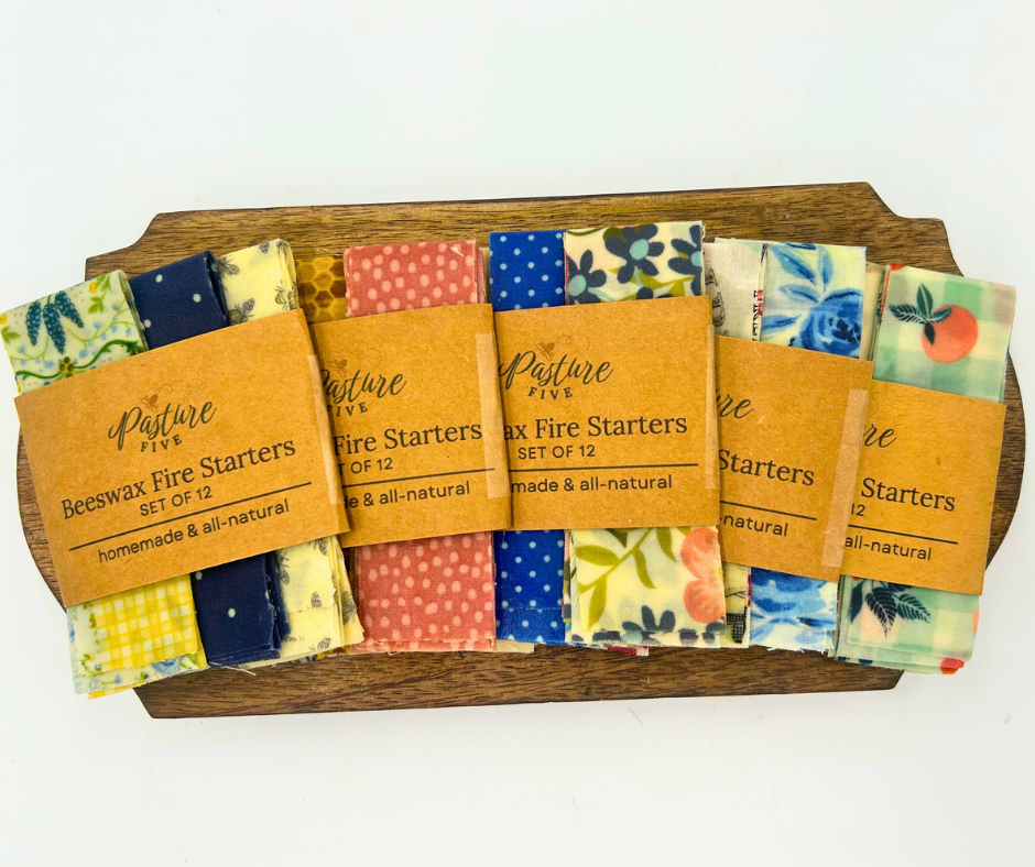 Set of beewax fire starters with colorful packaging on a wooden tray.