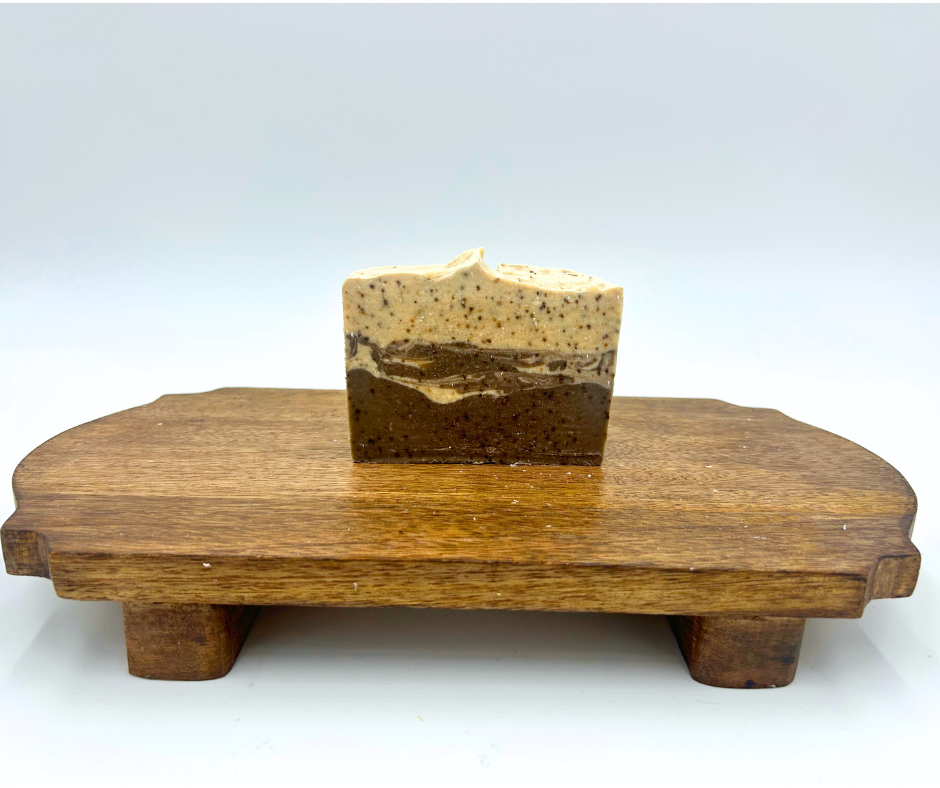 Bar of soap on a wooden soap dish against a white background
