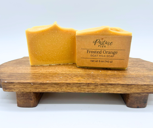 Two bars of Frosted Orange Goat Milk Soaps. One with a wrap and one with none. 
