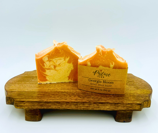 Two bars of orange soap on a wooden stand with a white background