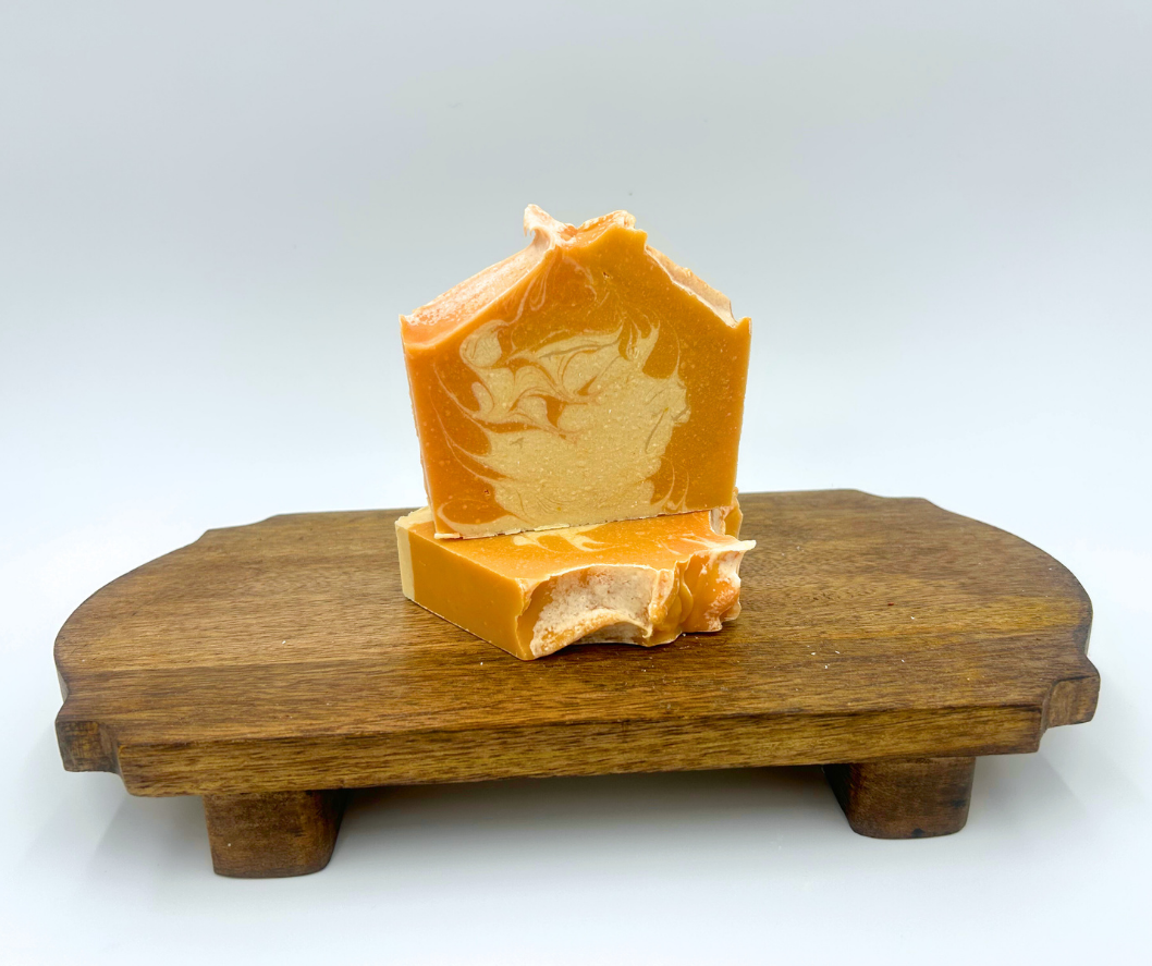 Orange soap bar on a wooden stand with a white background