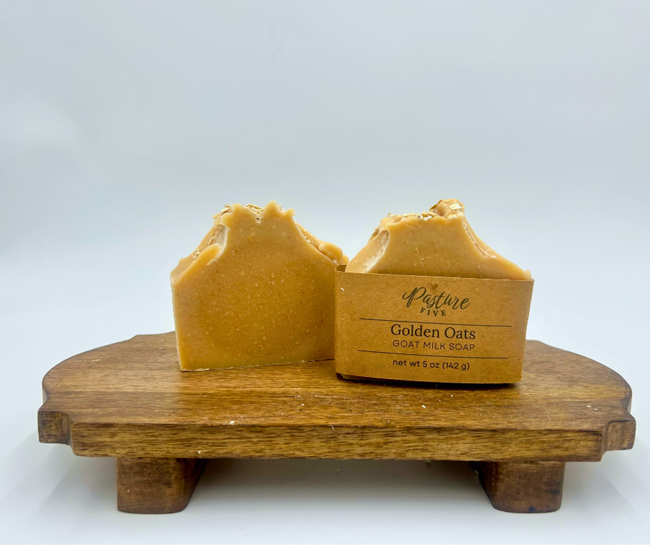 Two bars of Golden Oats soap on a wooden stand with a white background