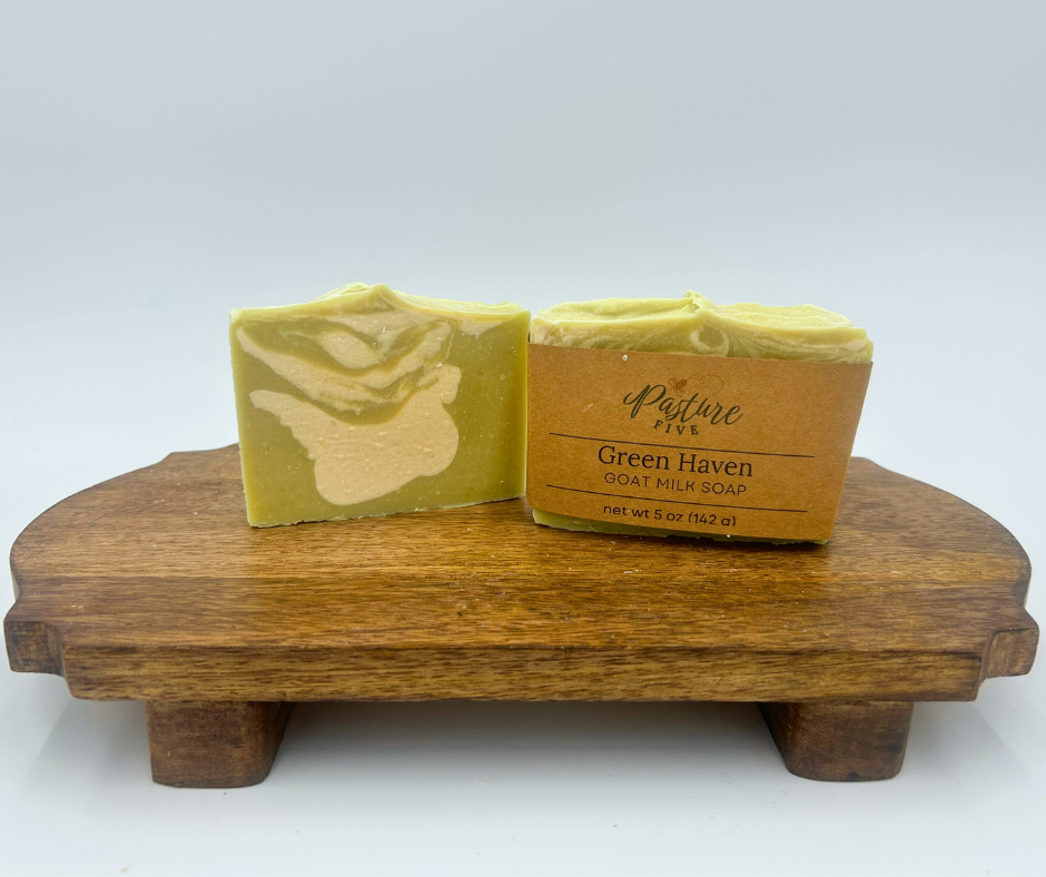 Two bars of soap on a wooden stand with 'Green Haven' branding.