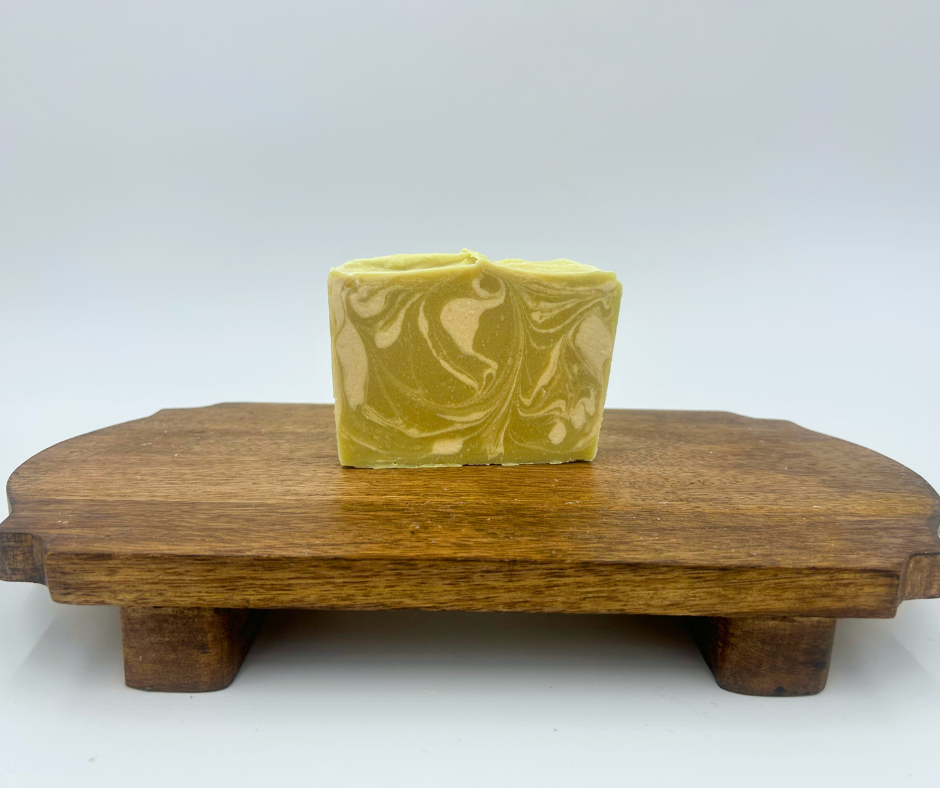 Green soap bar with a decorative pattern on a wooden stand against a white background