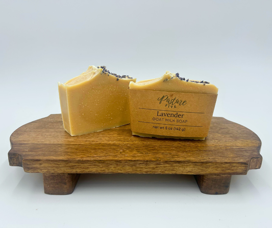 Two lavender bars of soap on a brown stand with a white background