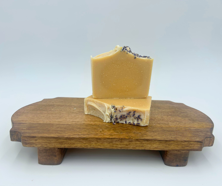 Two lavender bars of soap on a brown stand with a white background