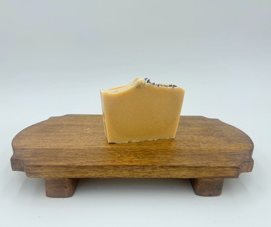 A Lavender bar of soap on a brown stand with a white background