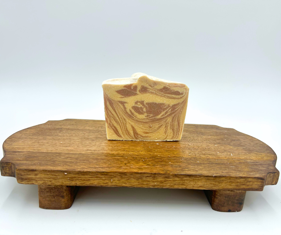 Bar of soap on a wooden soap dish against a white background