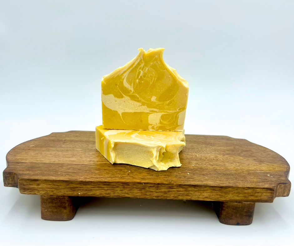 Two yellow soap bars on a wooden stand with a white background