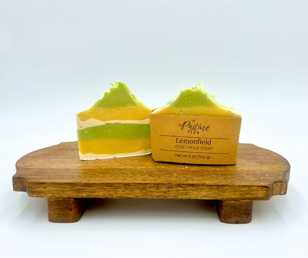 layered green, white, and yellow soap bars on a wooden stand with a label reading 'Lemonfield'.