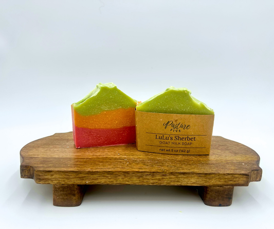 Three layered of green, orange and pink soap bars on a wooden stand with a white background