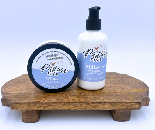 Two jars of Milkstone 'Pasture Five' lotion on a wooden stand with a white background