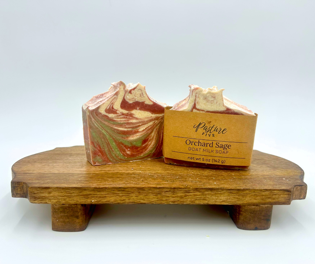 Two bars of soap with a swirl design on a wooden stand on a white background