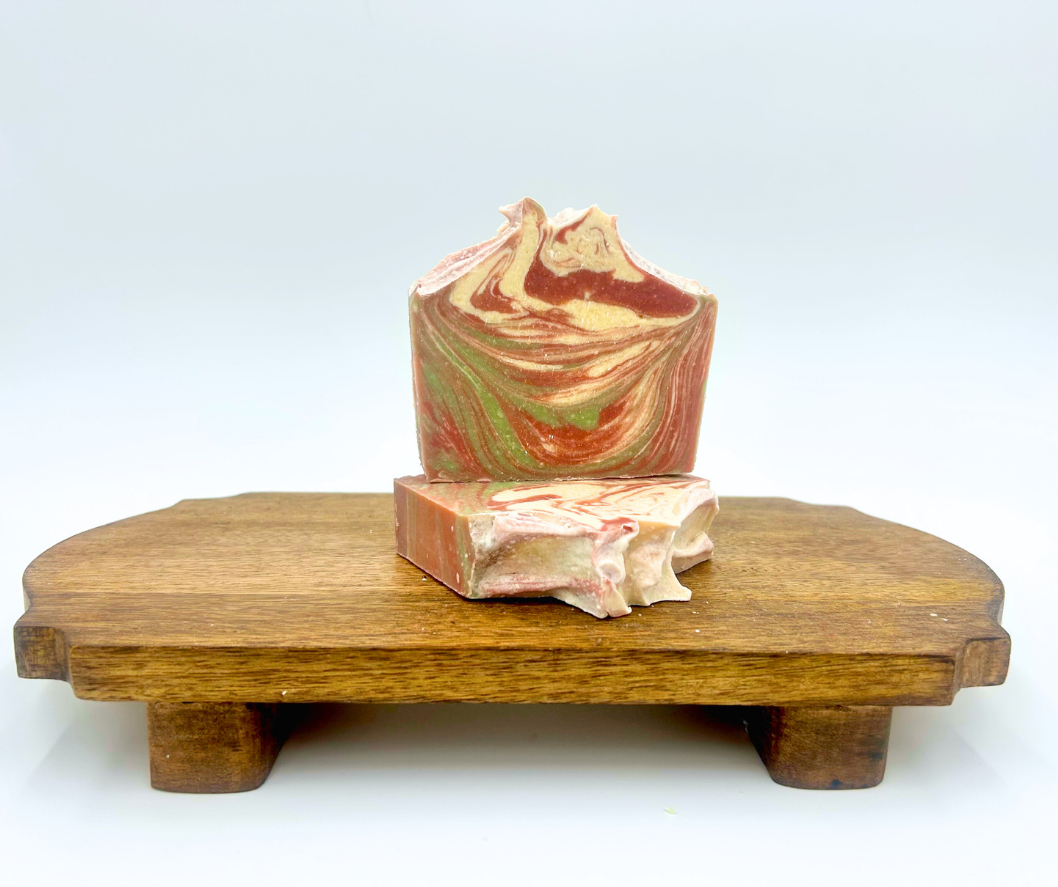 Swirled goat milk soap bar on a wooden stand with a white background