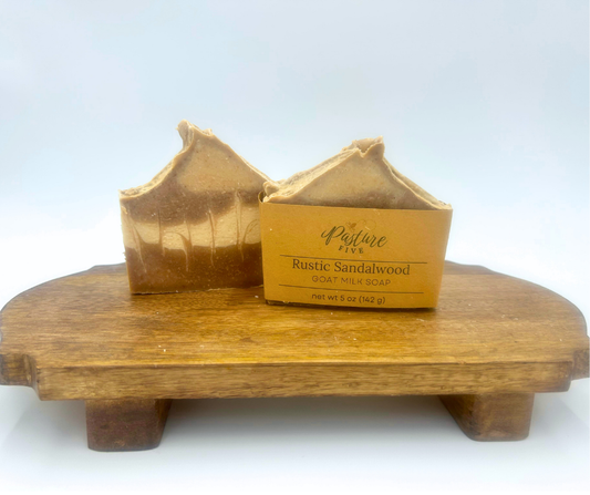 Two bars of Rustic Sandalwood soap on a wooden stand with a white background