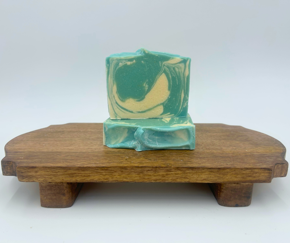 two blue and white swirl goat milk soaps on a brown stand 
