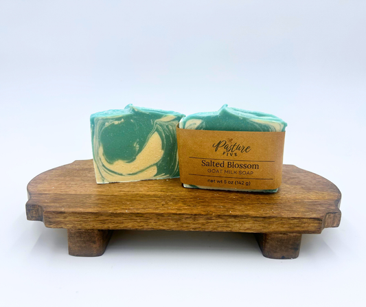 Two blue and white marbled soap bars on a wooden stand with a white background