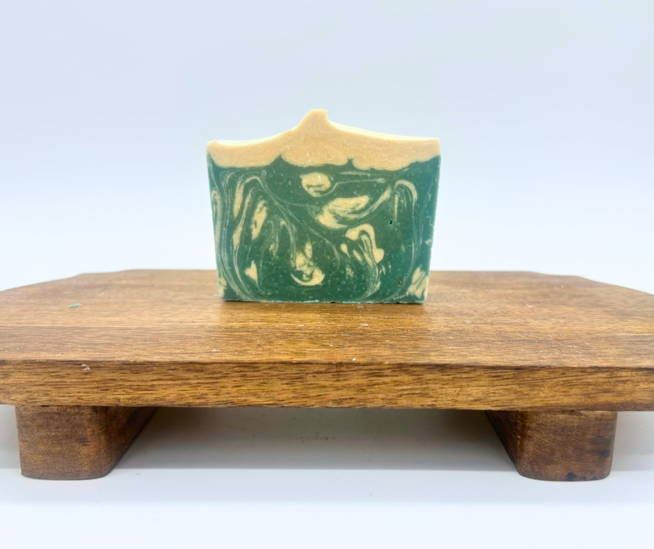 One bar of Snowy Spruce goat milk soap bars on a wood board. 
