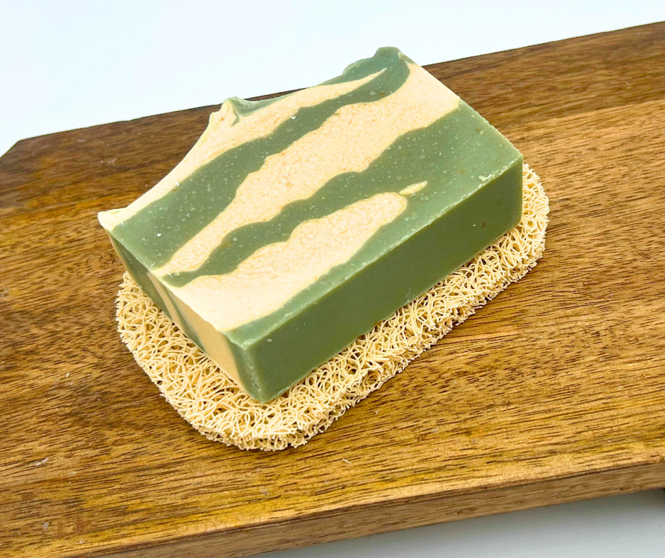A bar of soap on a soap saver pad on a wooden board with a white background