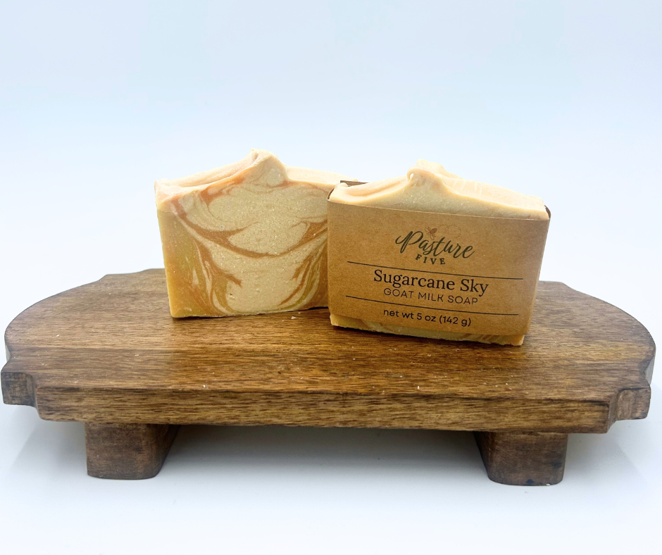 Two bars of soaps with white, yellow and orange on a wooden stand with a white background