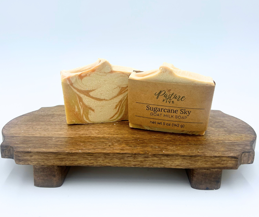 Two bars of soaps with white, yellow and orange on a wooden stand with a white background