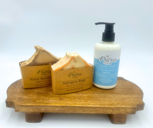 Pasture Five goat milk soap and lotion set on a wooden tray with a white background